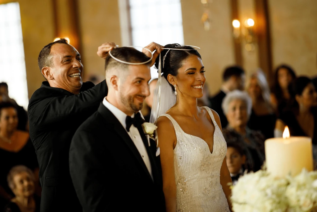 image of the crowning ceremony in a greek wedding where the koumbaro exchanges the crowns (stefana)