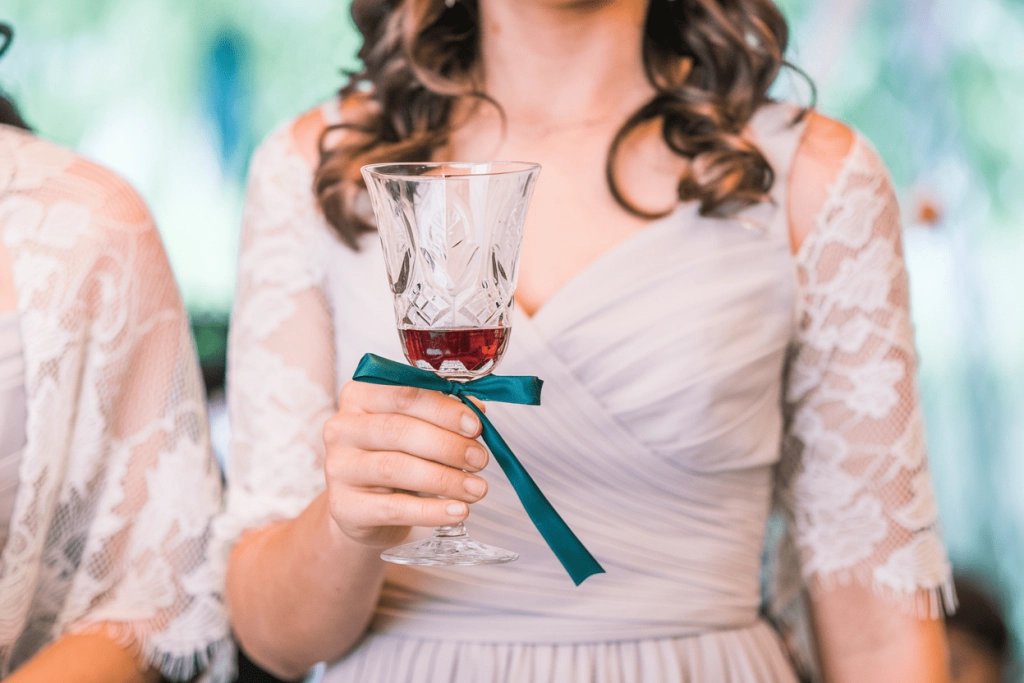 image of the koumbara holding a wine glass for the common cup ritual at a greek wedding