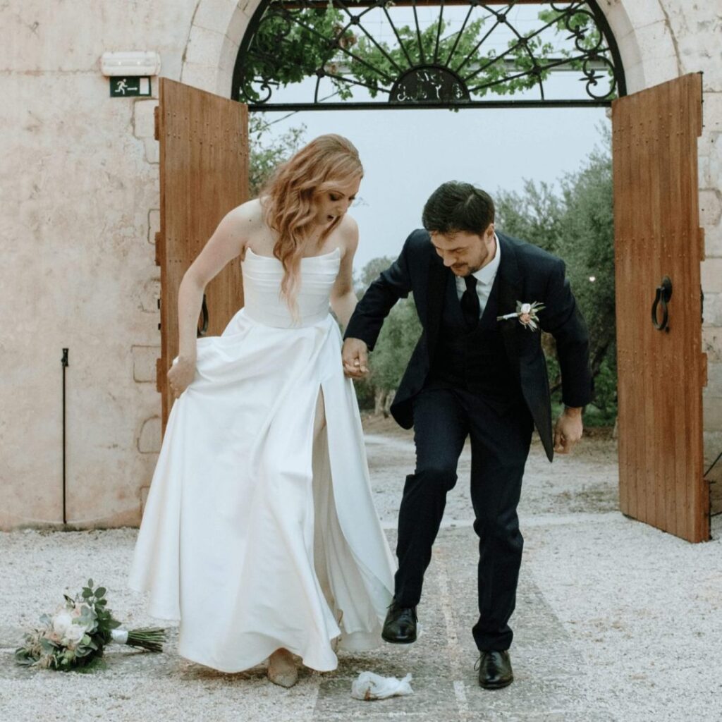 newly wed couple stomping on a pomegranate celebrating the greek tradition