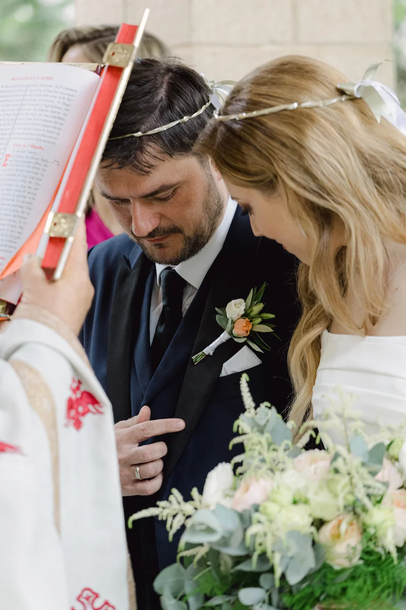 priest blessing the couple with a bible after the stefana have been put on