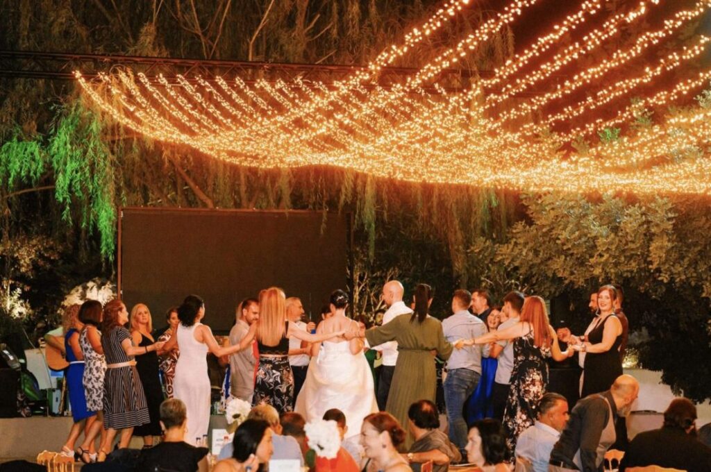 Guests join the circle dance at a Greek wedding. Nearly everyone gets pulled in, which is why the dance floor has to hold the whole guest list.