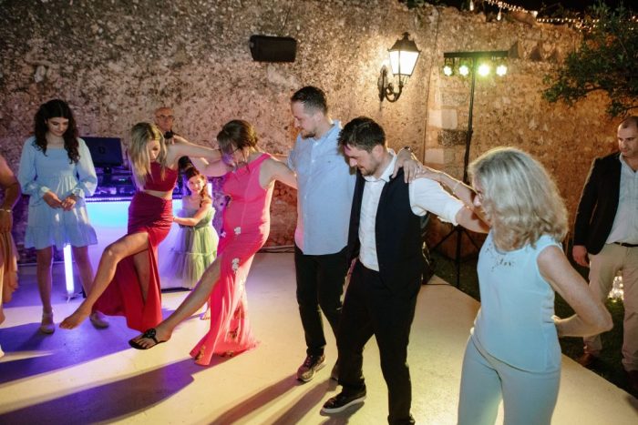an image of a greek wedding with the guests doing the traditional greek syrtaki dance