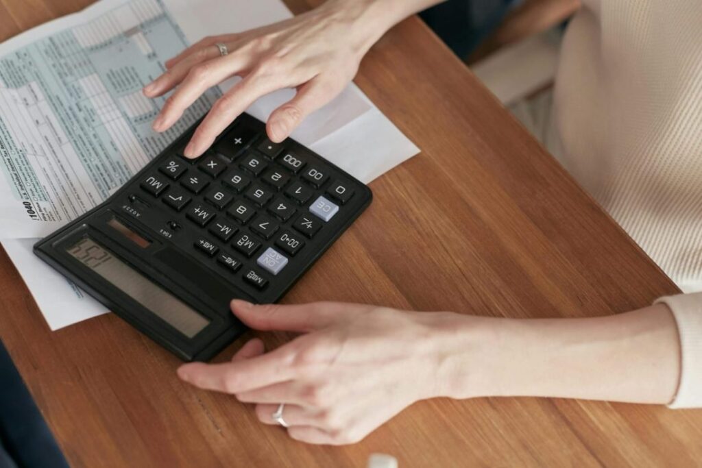 someone typing on a calculator to understand the hidden costs of a santorini wedding