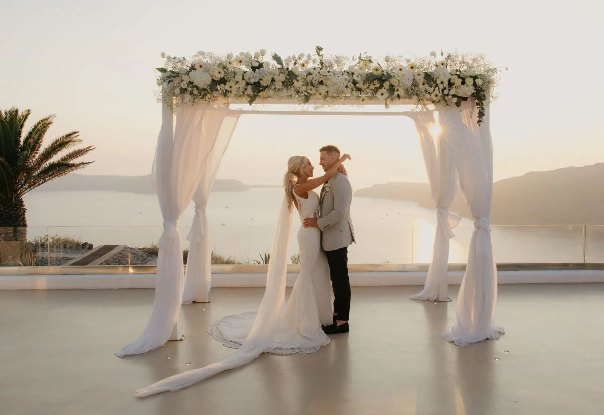 a wedding couple embracing in front of the aegean horizon at a santorini wedding venue