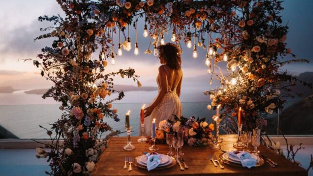 A beautiful bride in a wedding arch at a santorini wedding at dusk