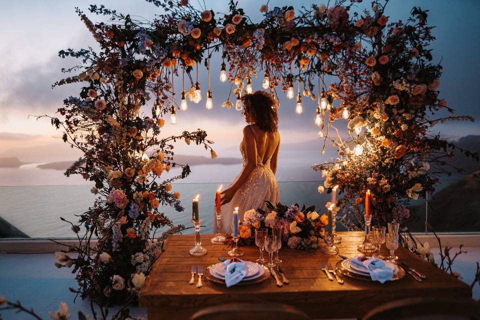 A beautiful bride in a wedding arch at a santorini wedding at dusk