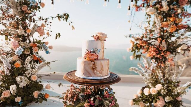 a beautifully decorated cake with flowers overlooking the santorini caldera