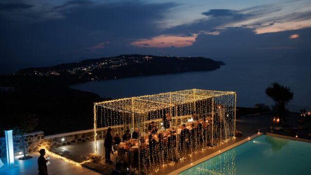 string lights and a santorini caldera view at a wedding