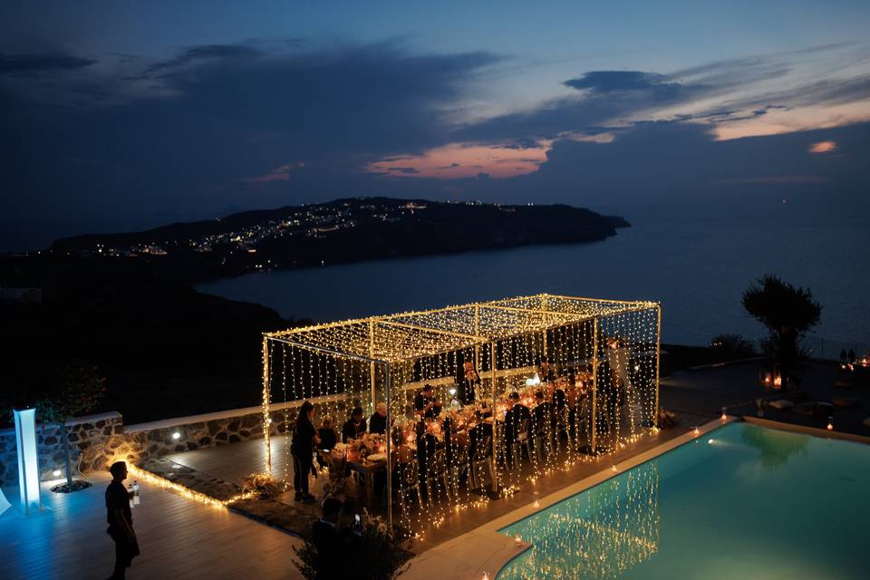 string lights and a santorini caldera view at a wedding