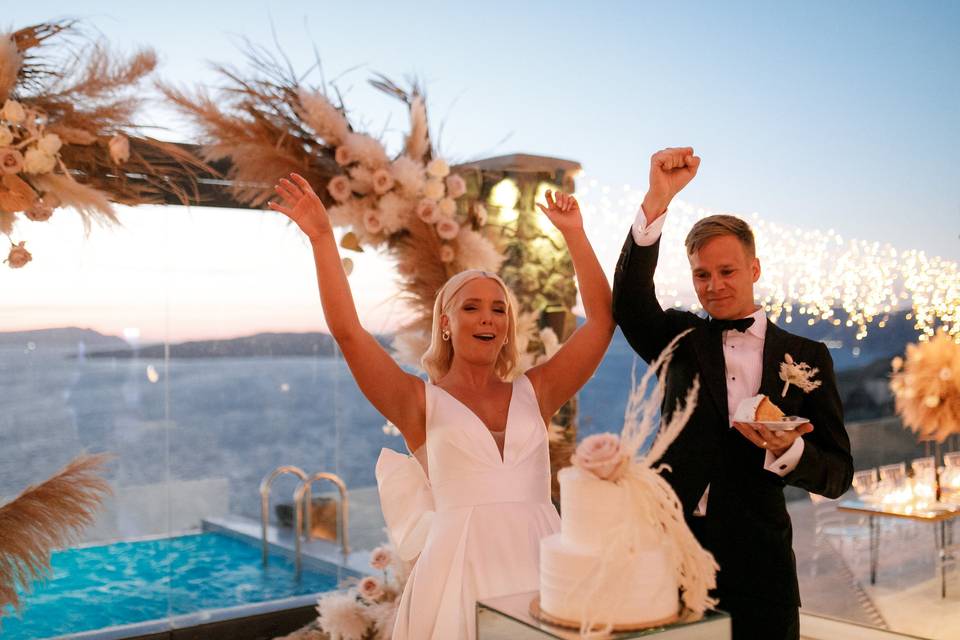 a couple about to cut the wedding cake in santorini