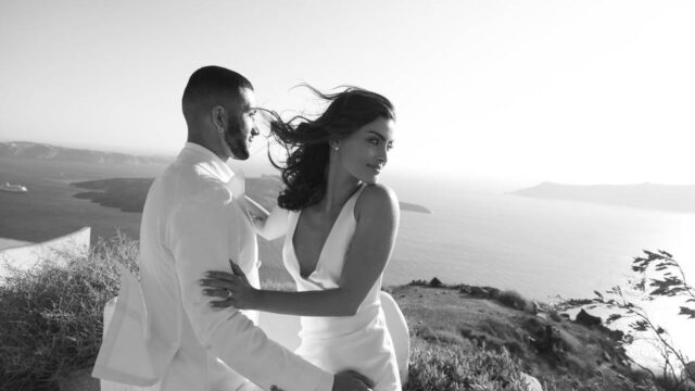 bride and groom posing in front of the santorini caldera