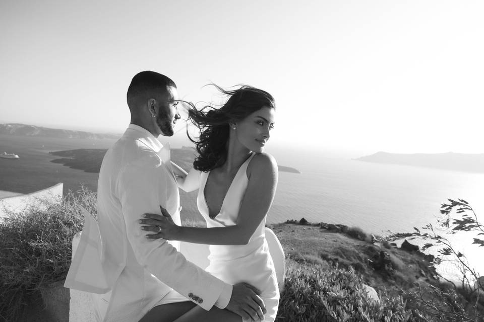 bride and groom posing in front of the santorini caldera