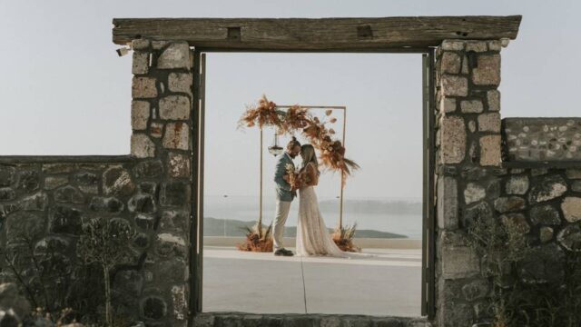 bride and groom embracing framed by a stone doorway in santorini