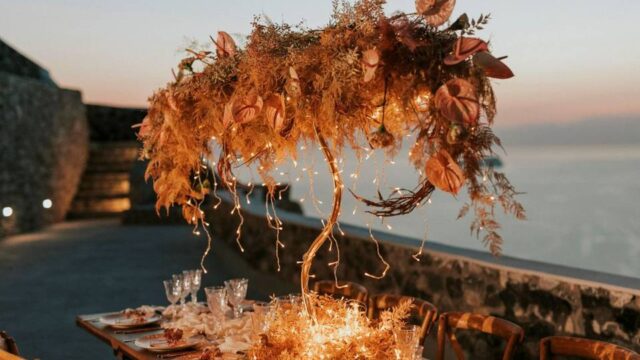 beautifully lit wedding table with flowers, candles and a santorini caldera backdrop