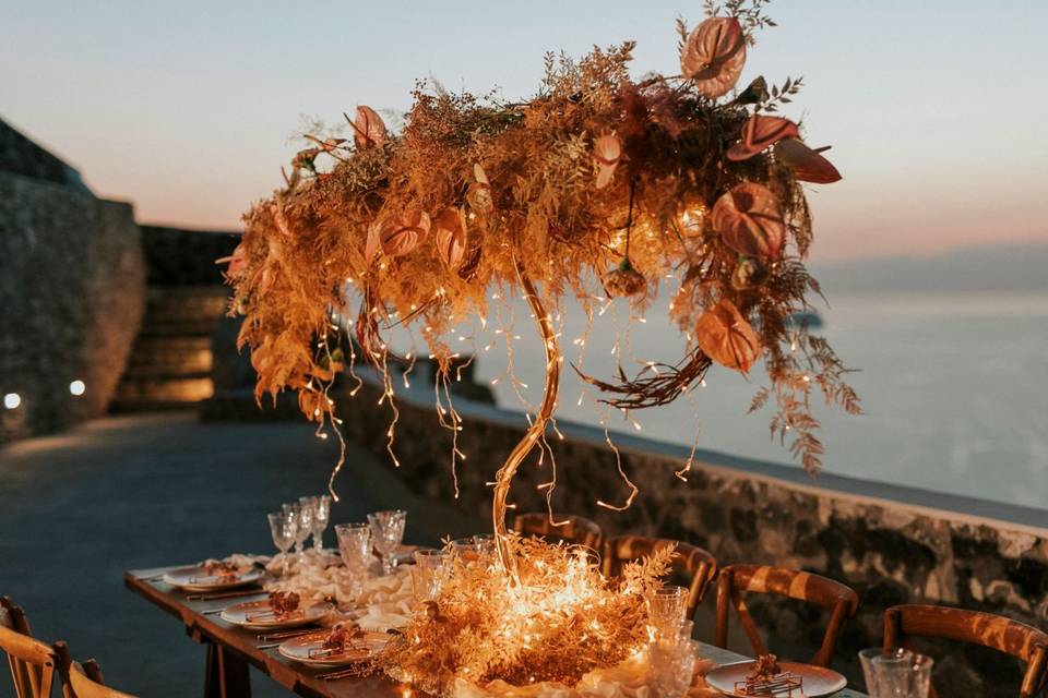 beautifully lit wedding table with flowers, candles and a santorini caldera backdrop