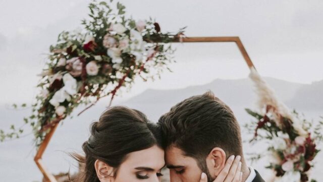bride and groom posing in front of a wedding arch