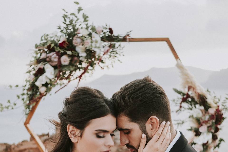 bride and groom posing in front of a wedding arch