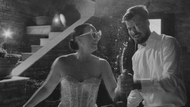 bride and groom popping champagne at their greek wedding reception