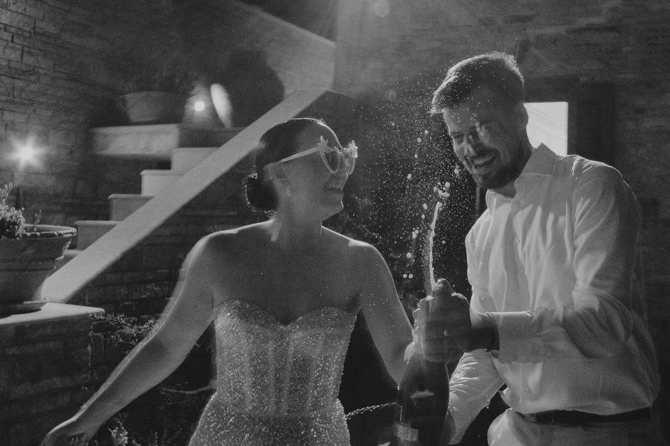 bride and groom popping champagne at their greek wedding reception