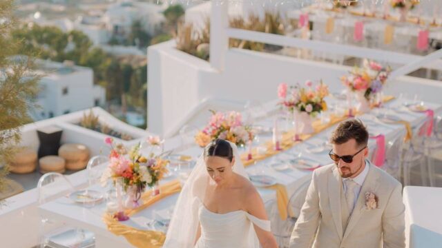 A newlywed couple holding hands at their wedding in greece