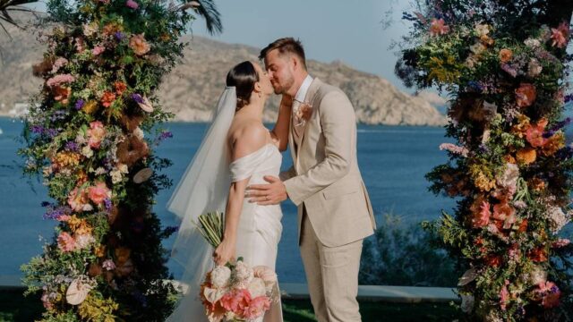 bride and groom kissing under a wedding arch in greece