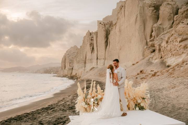 beach wedding in greece with a newlywed couple kissing by the sea