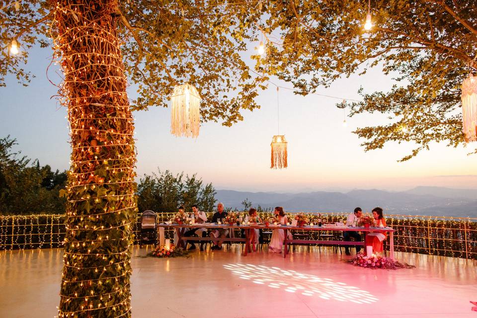 a colorfully lit greek wedding dance floor in the golden hour with the mountains in the background