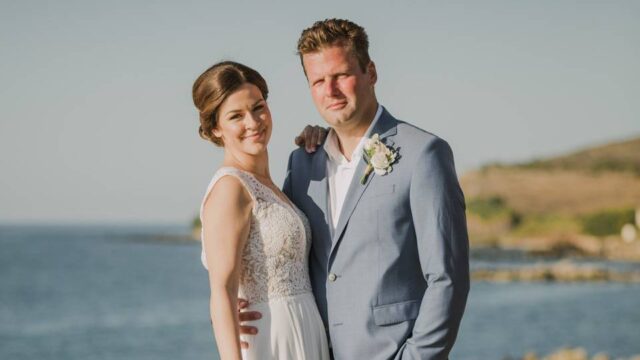 newlyweds posing in front of the agean sea in greece