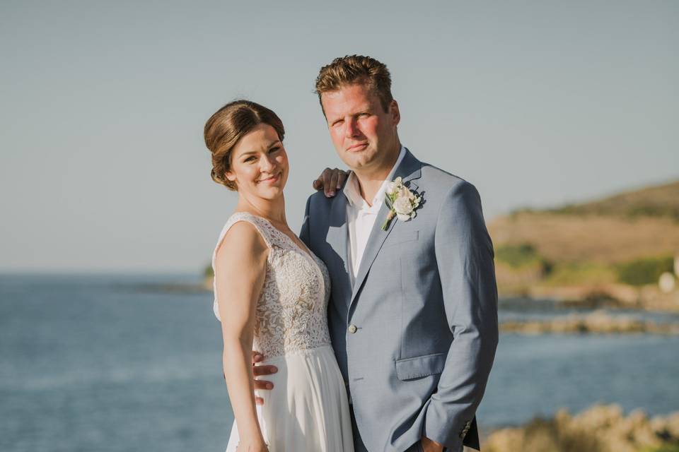 newlyweds posing in front of the agean sea in greece