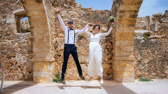 a wedding couple jumping amid greek ruins