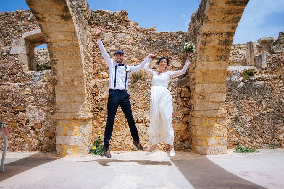 a wedding couple jumping amid greek ruins