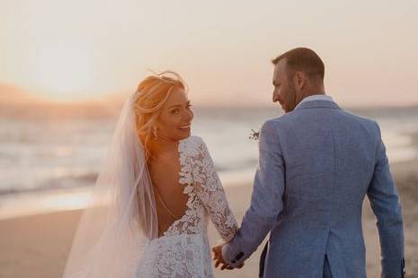 a couple strolling on a greek beach at their wedding