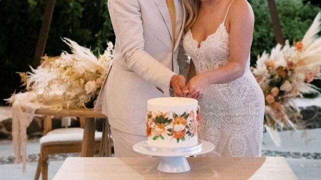 a couple cutting the cake at their wedding in greece