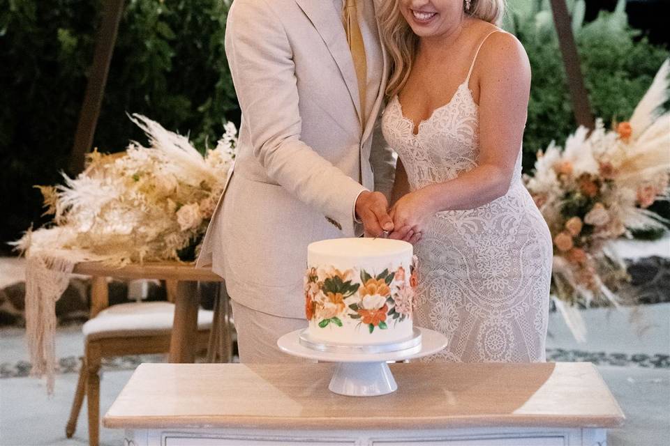 a couple cutting the cake at their wedding in greece