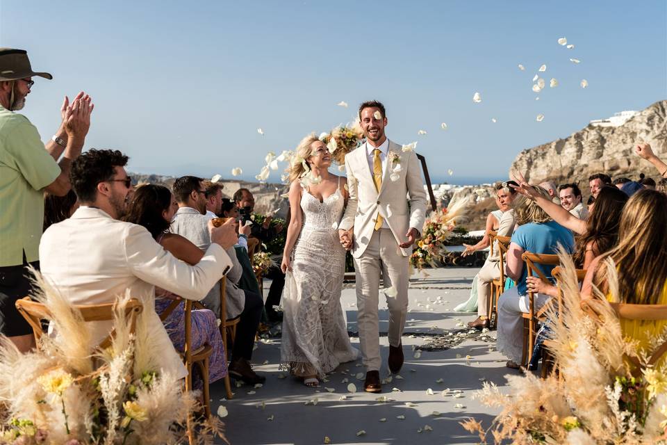 a newlywed couple walking down the aisle in greece