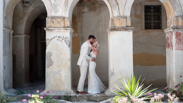 a newlywed couple in white embracing in greece