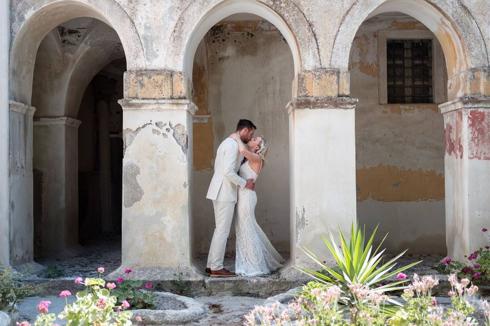a newlywed couple in white embracing in greece