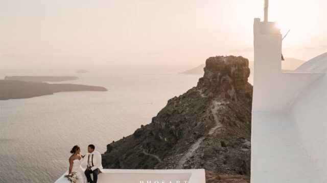 a newlywed couple look at the aegean sea in santorini