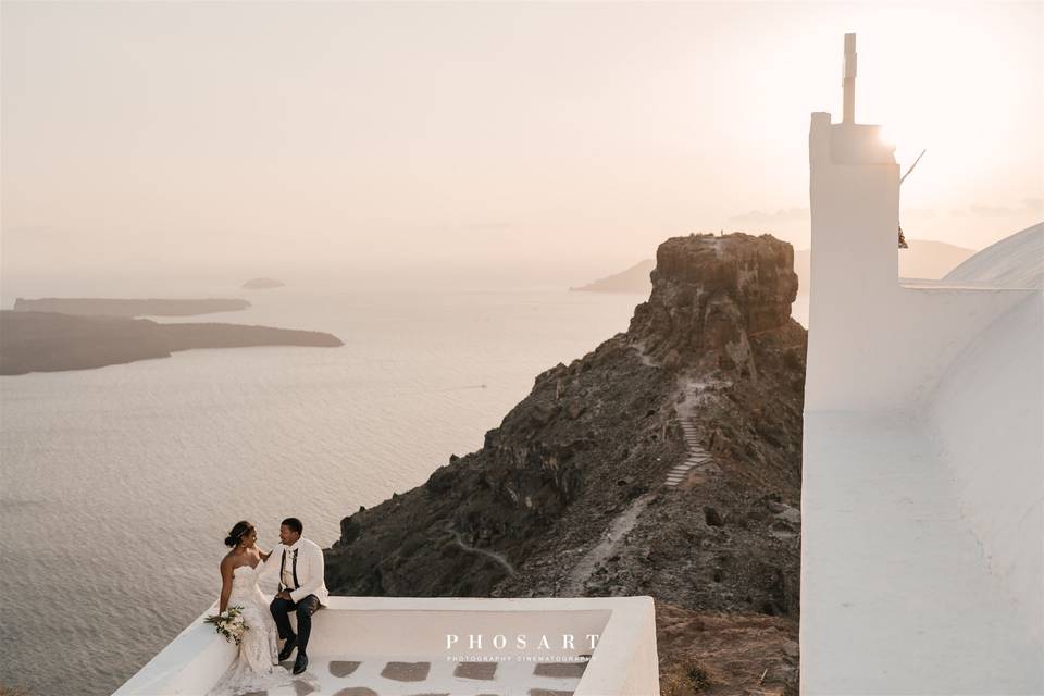 a newlywed couple look at the aegean sea in santorini