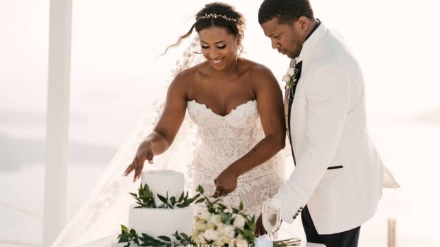 a couple cutting the cake at their wedding in santorini