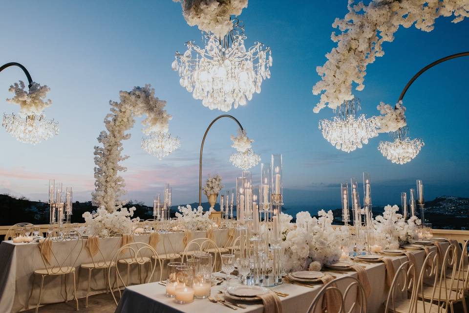 chandeliers hanging over the tables at a santorini wedding reception