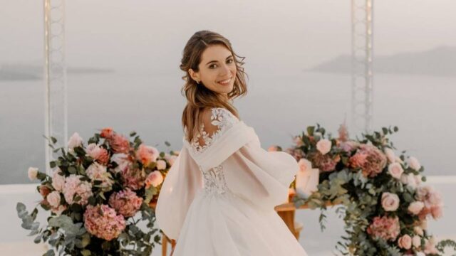 a bride among flowers with the sea in the backdrop at her greek wedding