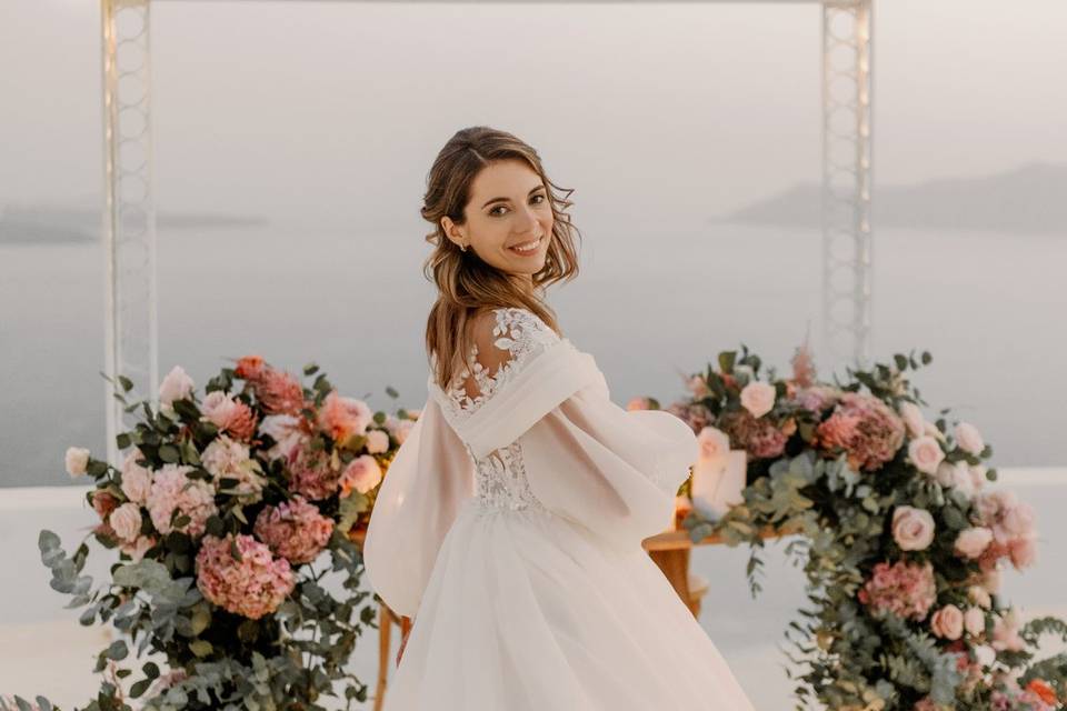 a bride among flowers with the sea in the backdrop at her greek wedding