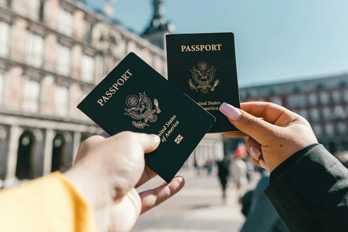 a couple holding two passports with a background which is likely in europe with classical buildings
