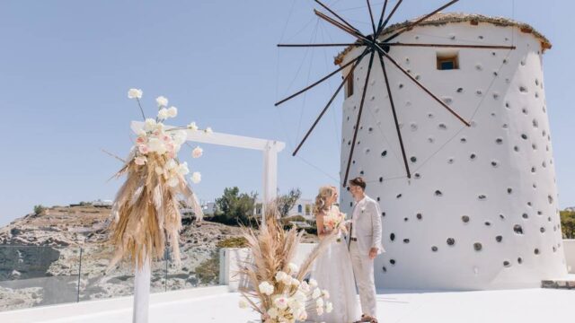 a wedding couple in front of a whitewashed greek windmill