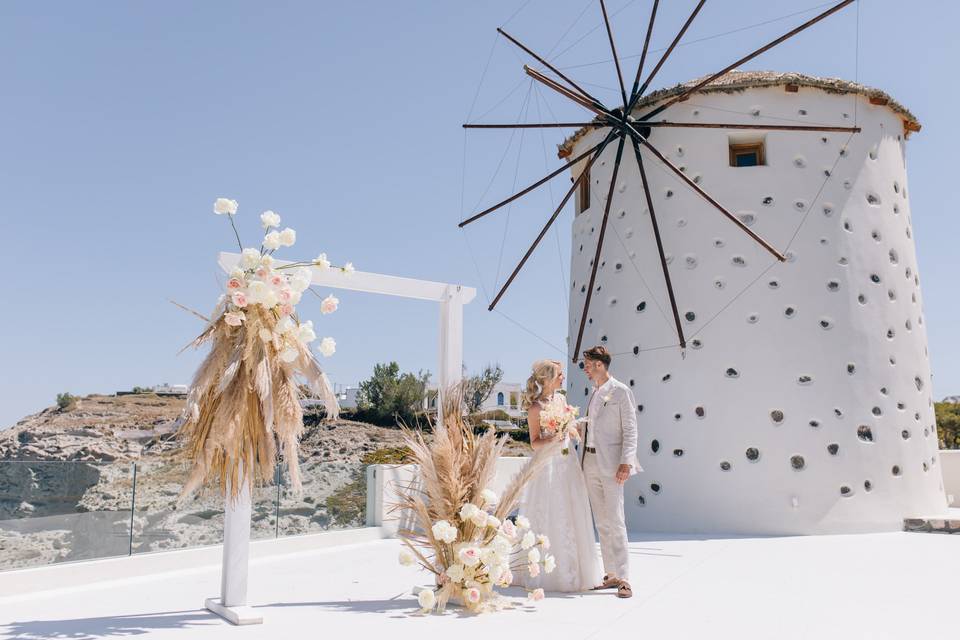a wedding couple in front of a whitewashed greek windmill