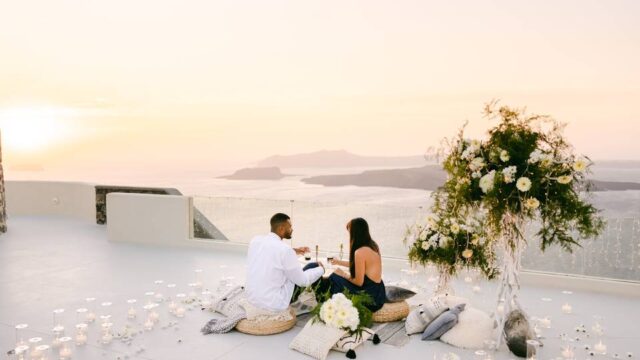 a wedding couple lounging in front of the santorini caldera