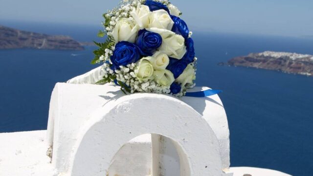 a greek chapel decorated with flowers with an aegean sea backdrop