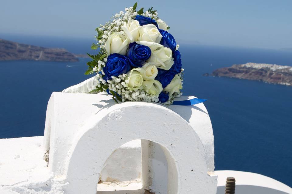 a greek chapel decorated with flowers with an aegean sea backdrop
