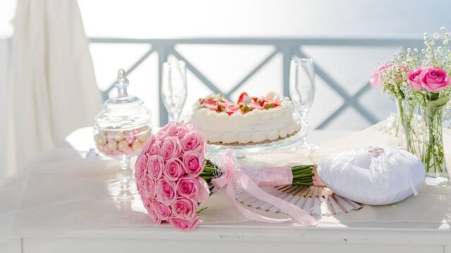 a greek wedding celebration table with a cake and flower bouquet